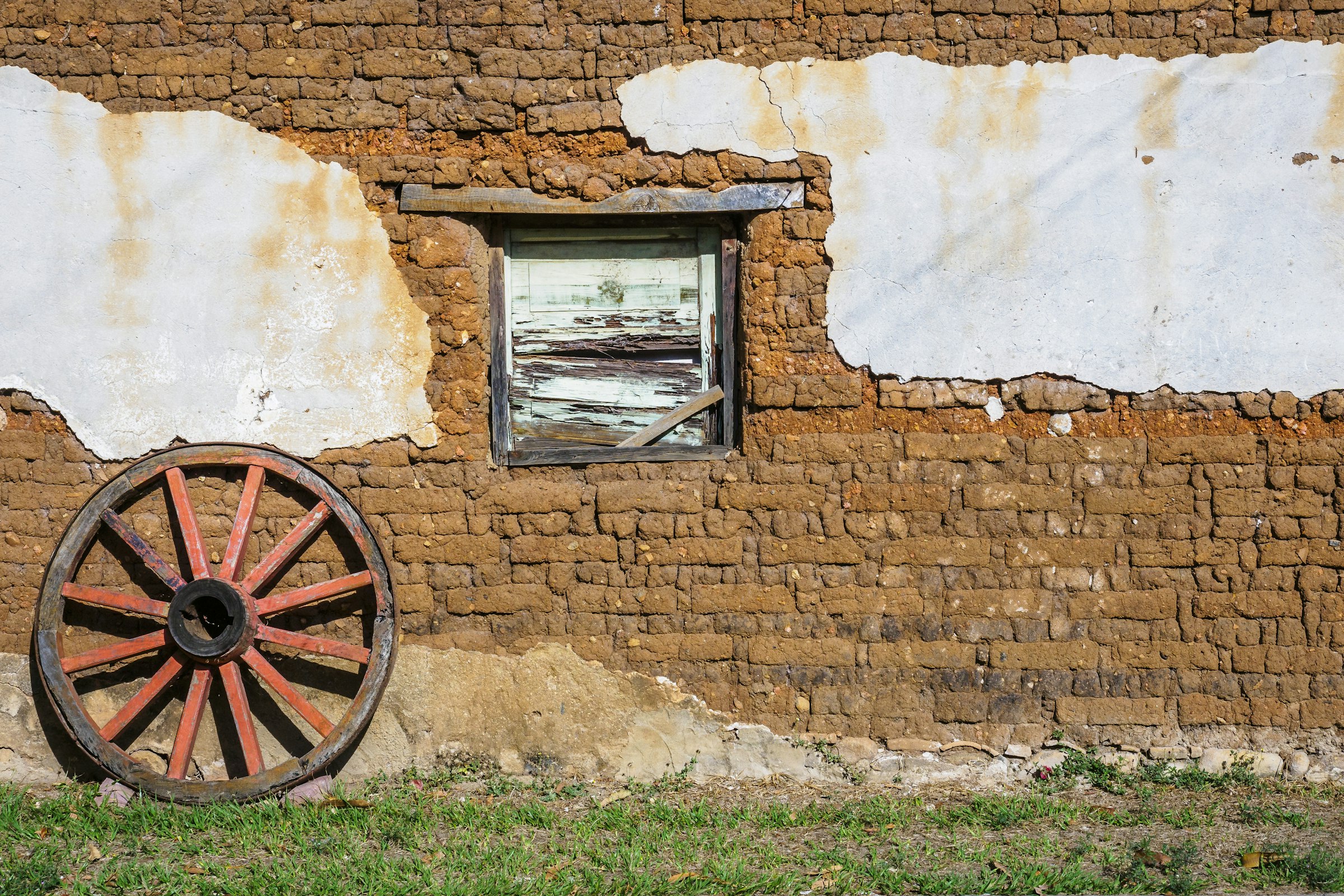 Una pared de adobe y una rueda de carreta en Suchitoto